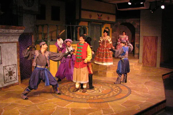 A theatrical scene with actors in colorful costumes on stage.