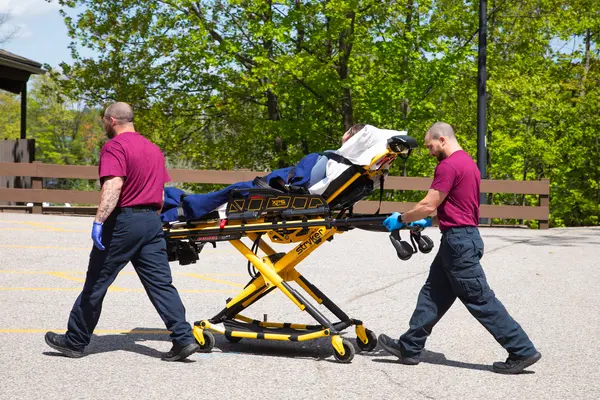 Paramedics transport a patient on a stretcher outdoors.