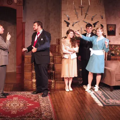 Stage play scene with five actors in a living room setting.