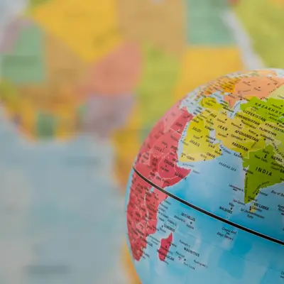 Colorful globe with close-up of Europe and Africa, blurred map background.