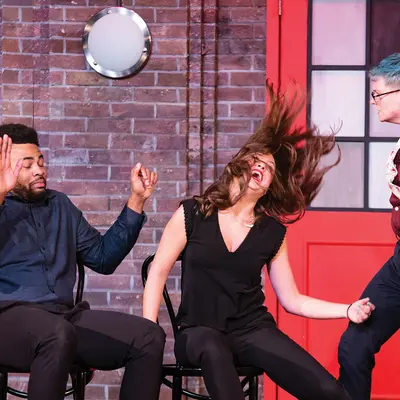 Three people performing on stage, one with hair mid-flip.