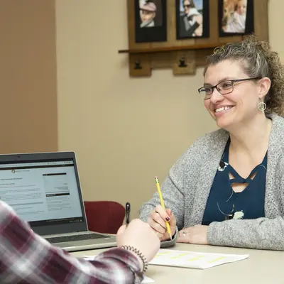 Financial Aid Advisor with student at a table, smiling and discussing.