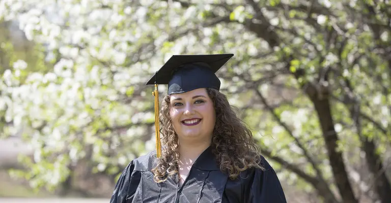 Female graduate in front of crab apple tree