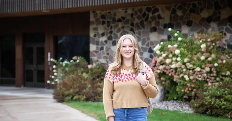 female student standing in front of a campus building