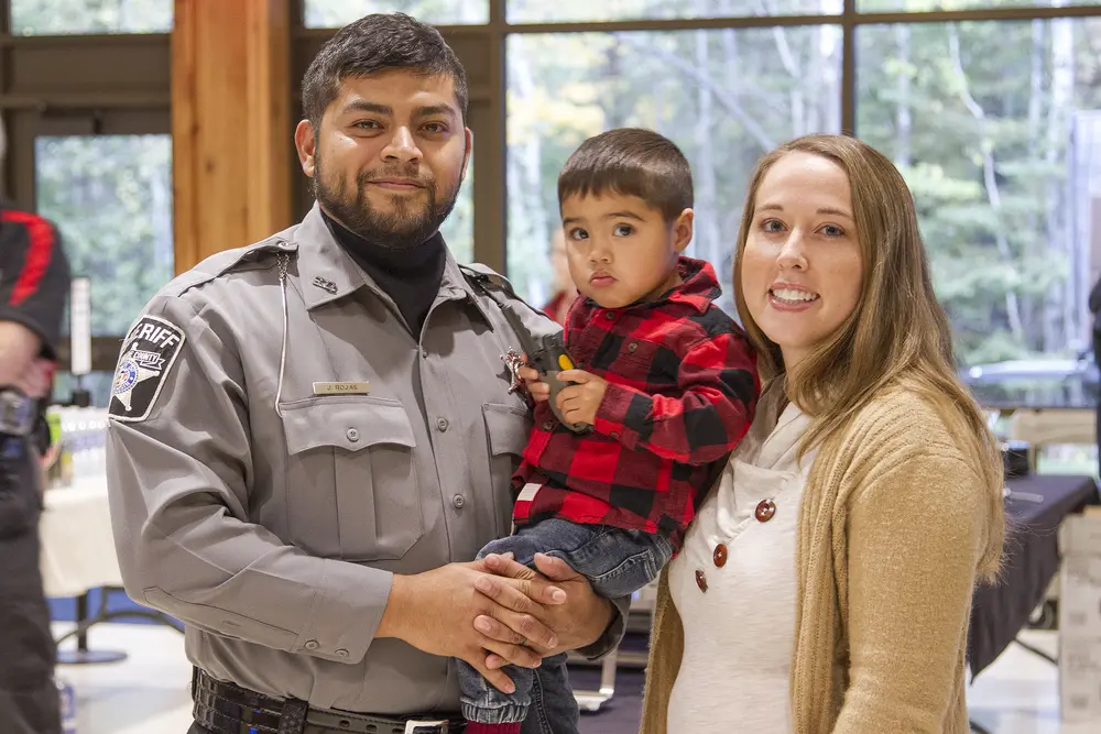 Academy graduate with his family, holding his son. 