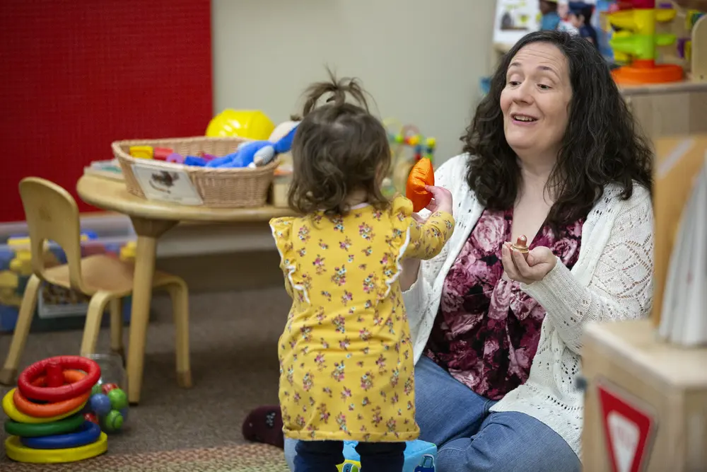 Early Childhood Education student engaging with child in colorful playroom.