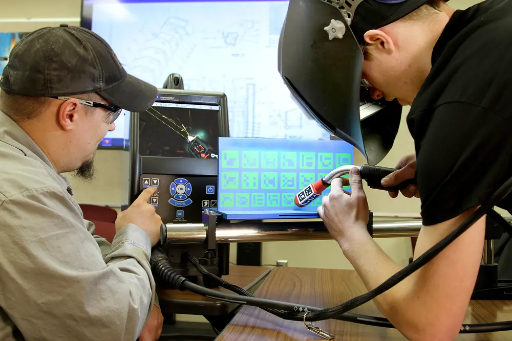 Two men working at a welding machine, focused and engaged.
