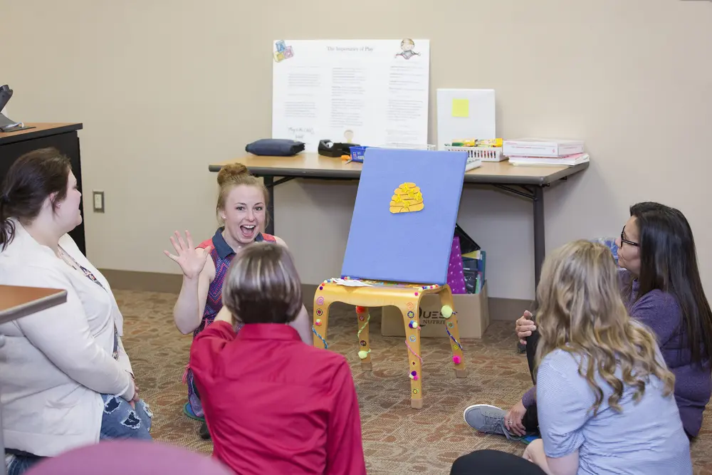 Early Childhood Education class sitting in a circle, one woman gesturing and smiling.
