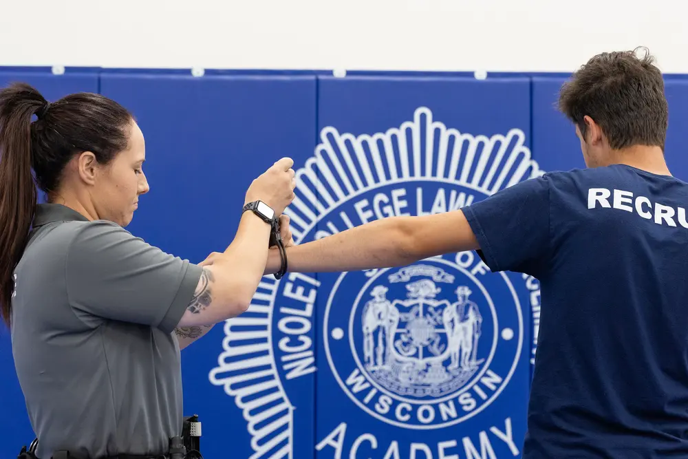 Instructor and trainee practicing defensive tactics in a gym.