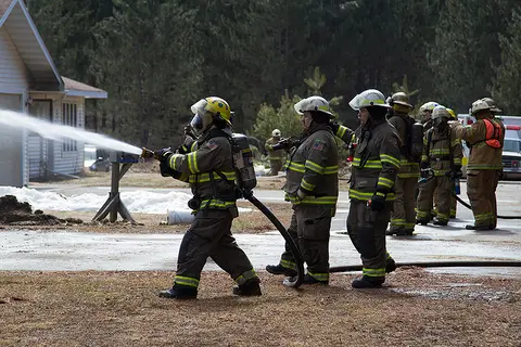 Firefighters spraying water on a house in training exercise.