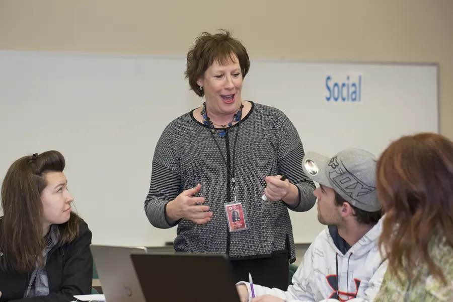 Female Business Management instructor engaging with students in a classroom setting.