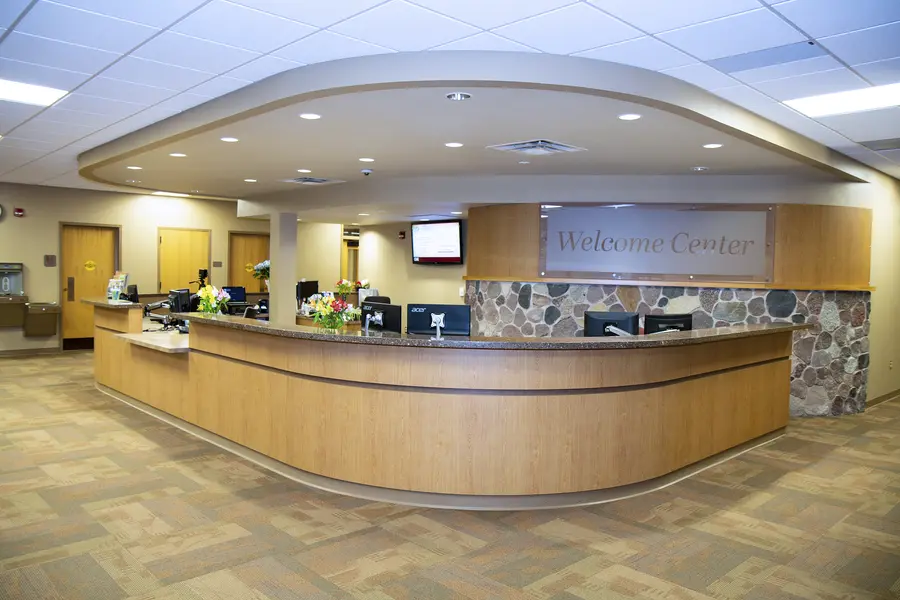 Wide, curved reception desk in a well-lit lobby with sign reading "Welcome Center."