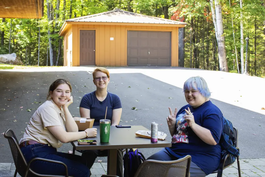 Three female students sitting at the Lakeside Center patio, smiling and eating lunch.