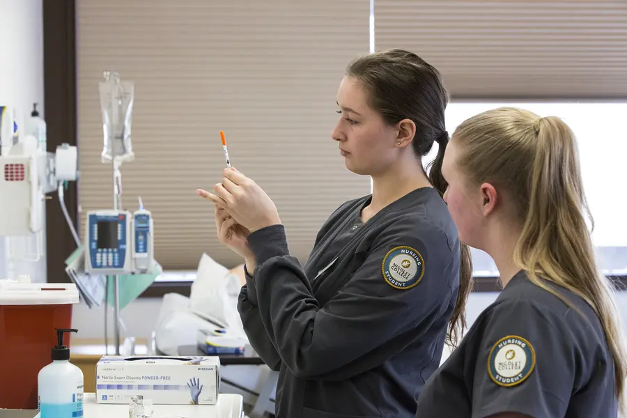 Two nursing students preparing a syringe in a medical setting.